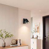 Punto de luz de acento negro mate sobre mueble recibidor en pasillo de diseño limpio.