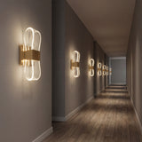 Decoracion de pared en pasillo con luz LED bidireccional y acabado dorado espejo.