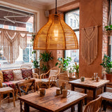 Serie de lámparas de rattan Brisa en comedor con mesas de madera y decoración rústica.
