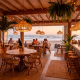 Serie de luminarias colgantes artesanales en comedor de playa con luz natural y madera.
