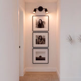 Puntos de luz focal dirigidos hacia obras de arte en pared dentro de galería residencial.