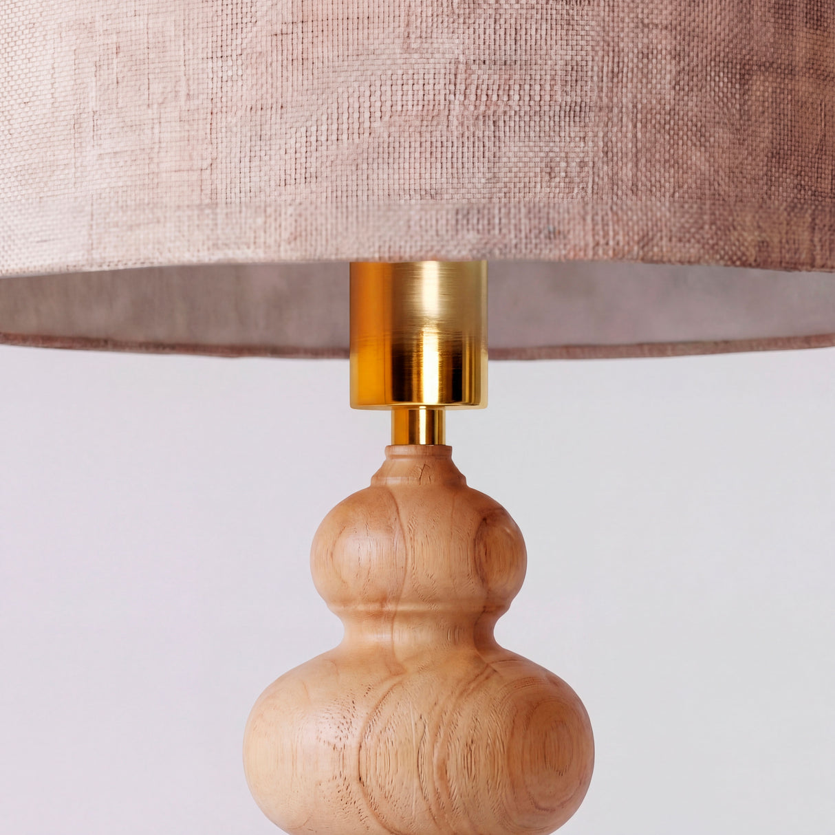 Close-up del mástil de madera clara y el herraje metálico superior con pantalla de lino.