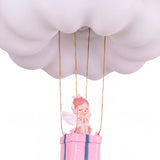 Primer plano de la figura decorativa del ángel en la cesta bajo la nube iluminada.