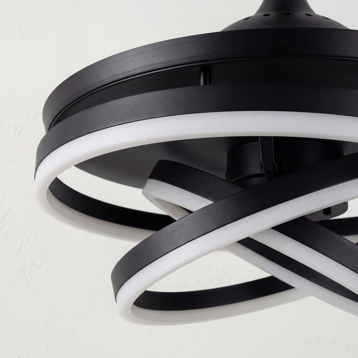 Detalle de los anillos LED entrelazados con acabado negro mate y difusor de luz suave.