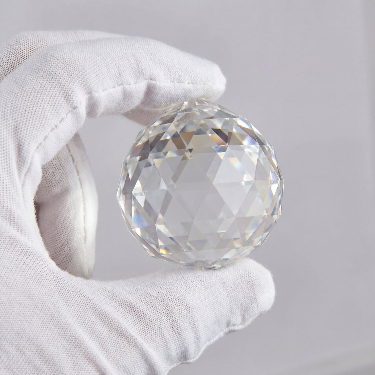 Mano sosteniendo una esfera de cristal facetado para ventilador de techo premium.