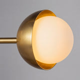 Primer plano de la esfera de vidrio opalino encajada en la copa metalica dorada de la lampara Nova.