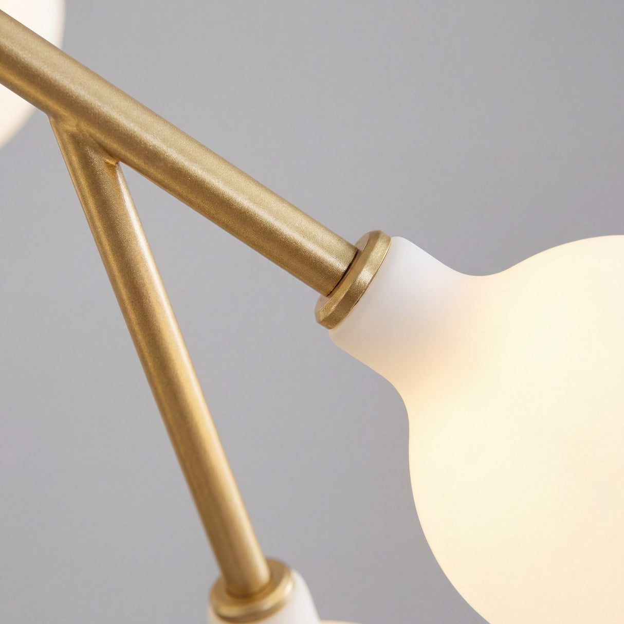 Detalle de acabado dorado mate y union de ramas en lampara de diseño moderno.