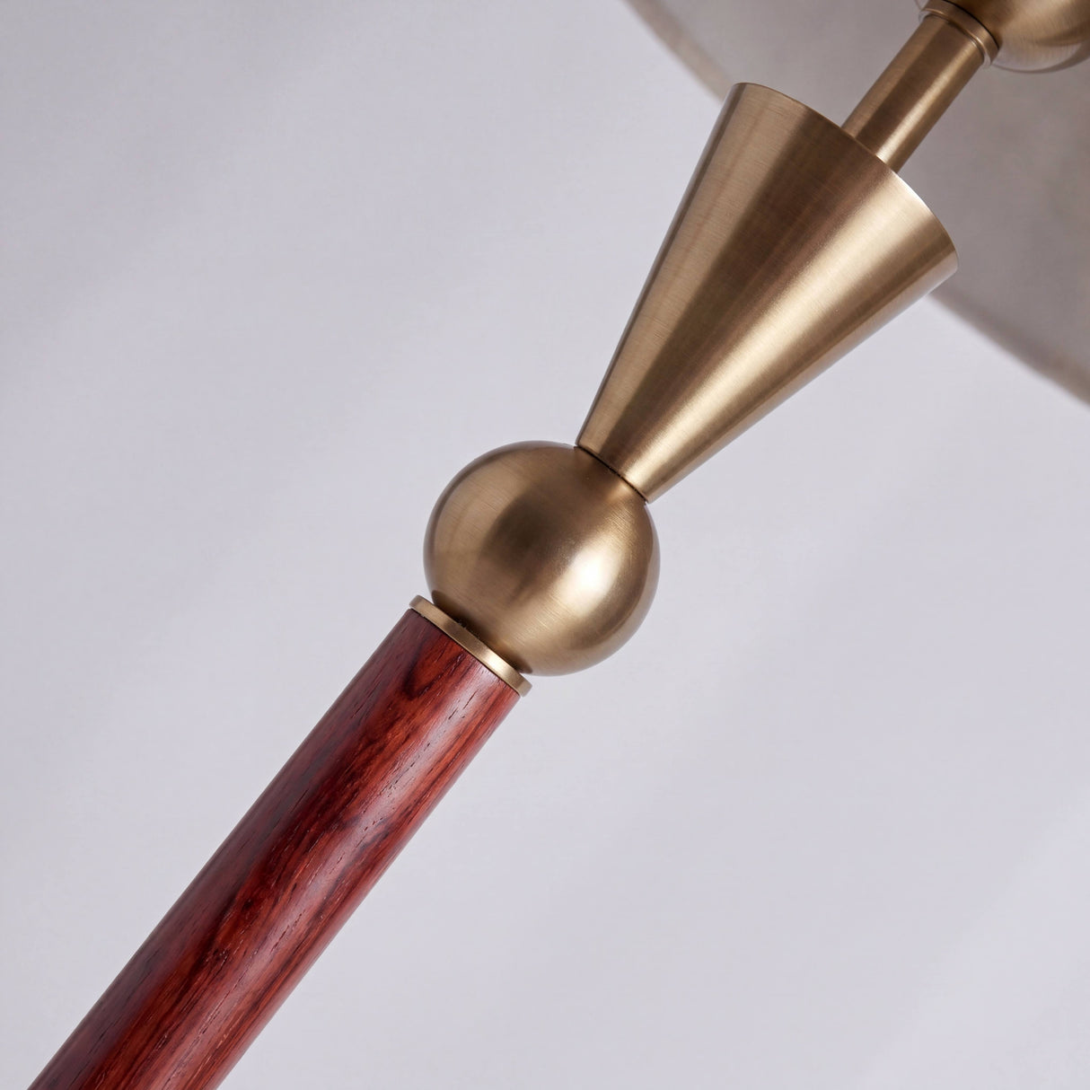 Detalle técnico de junta metálica dorada y cuerpo cilíndrico de madera con acabados premium.