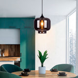 Luminaria cilíndrica de vidrio gris integrada sobre una mesa de comedor circular contemporánea.