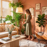 Salón de estilo biofílico con plantas iluminado por lámpara de pie curva con acabados premium.
