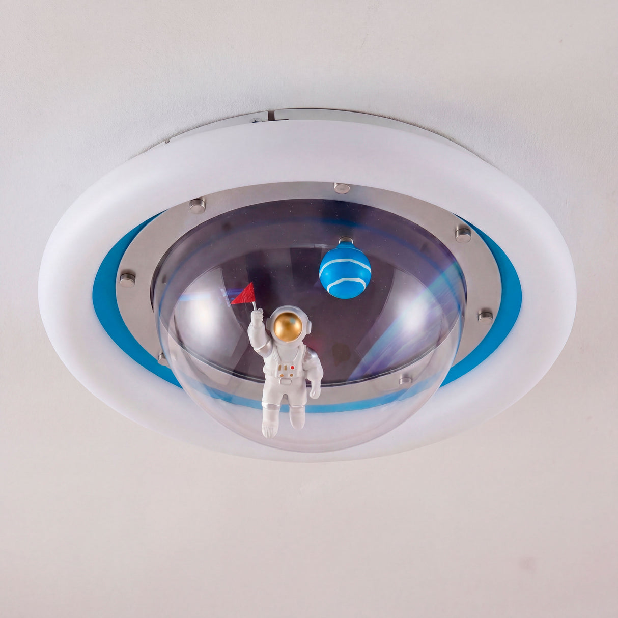 Detalle del astronauta y planetas decorativos bajo la cúpula central de la lámpara.