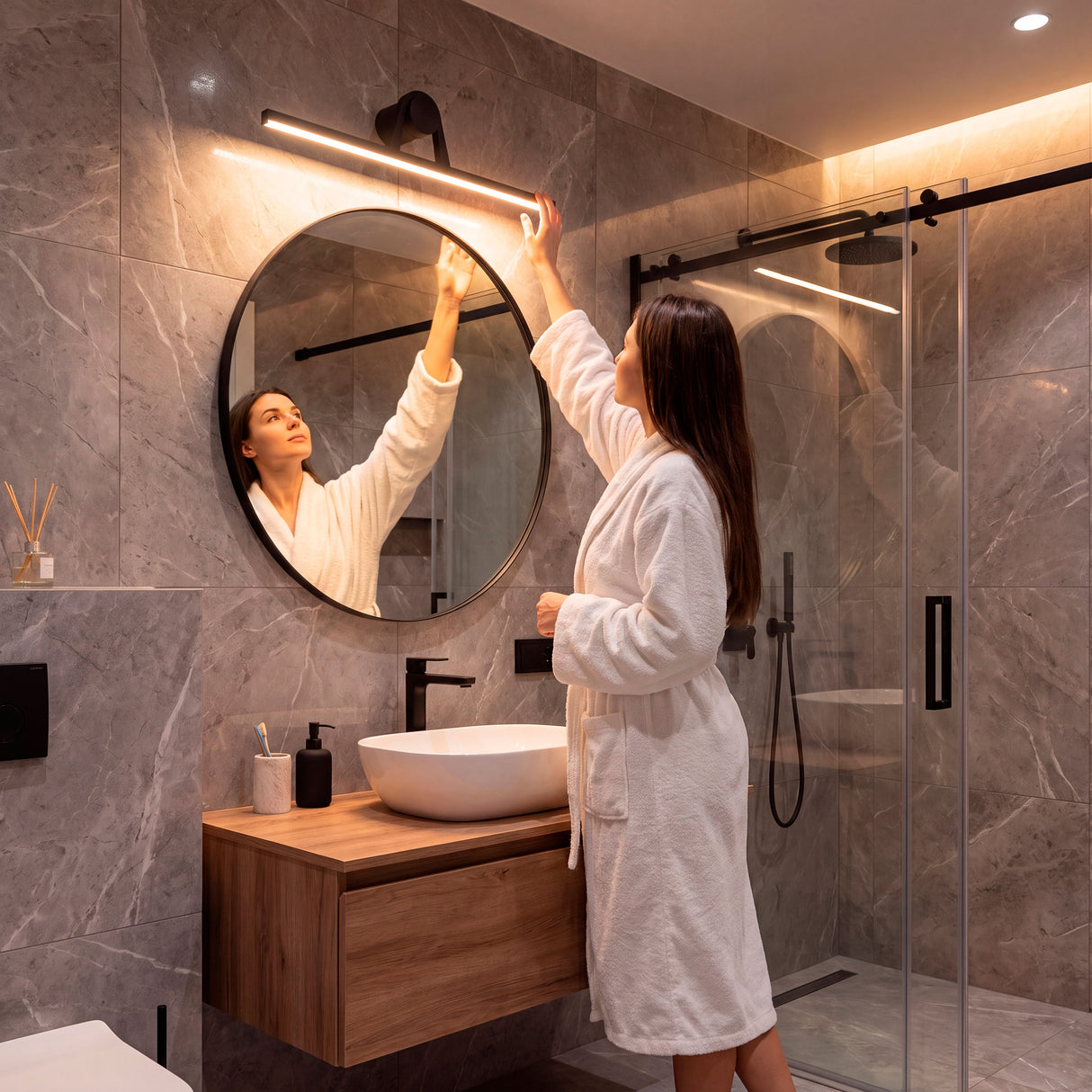 Barra de luz difusa aportando confort óptico sobre espejo redondo en un baño con acabados premium.