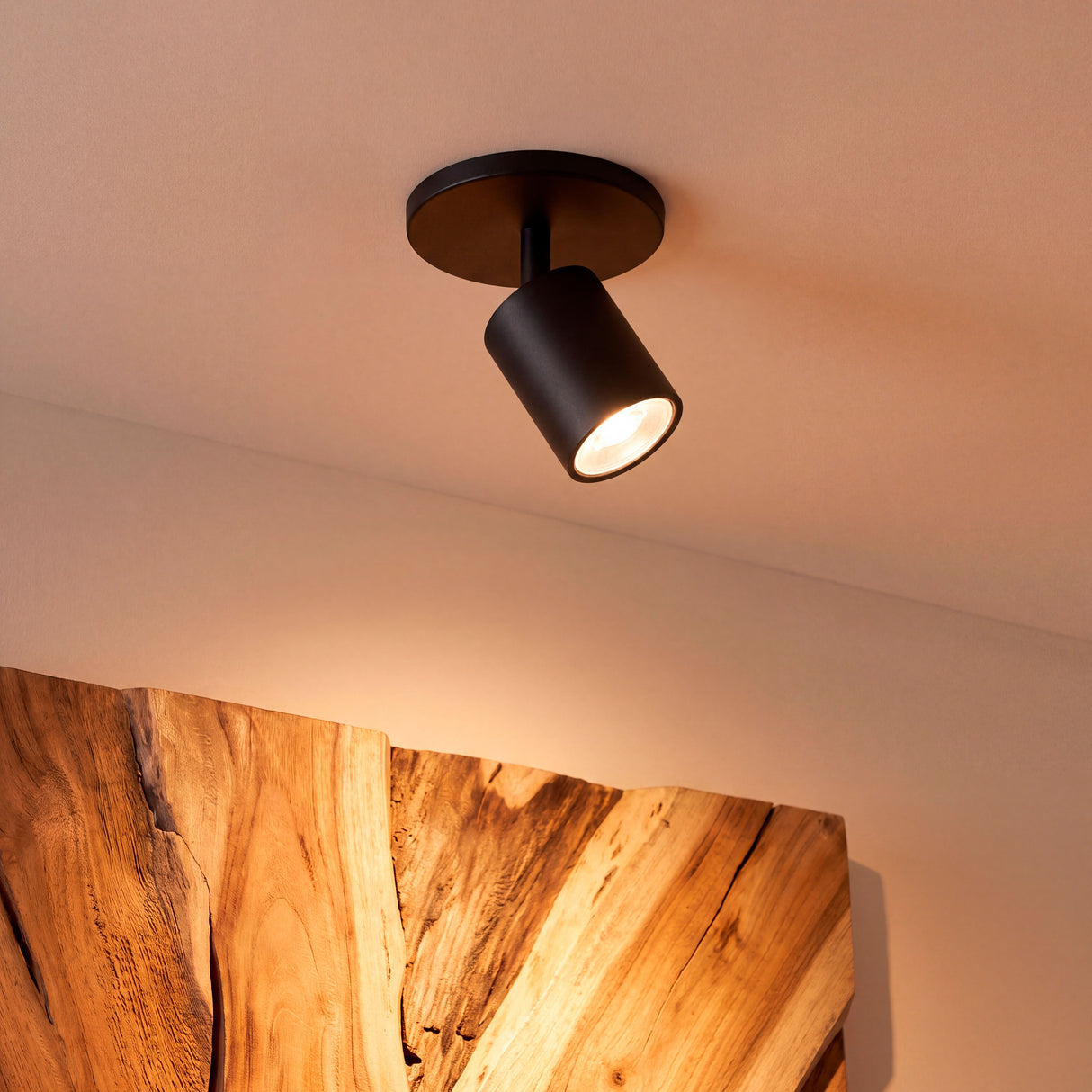 Foco orientable de sobreponer con diseño minimalista proyectando luz cálida directa.