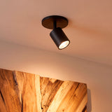 Foco orientable de sobreponer con diseño minimalista proyectando luz cálida directa.