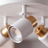 Primer plano de reflector cilíndrico en blanco mate con detalle de anillo dorado y rótula articulada.