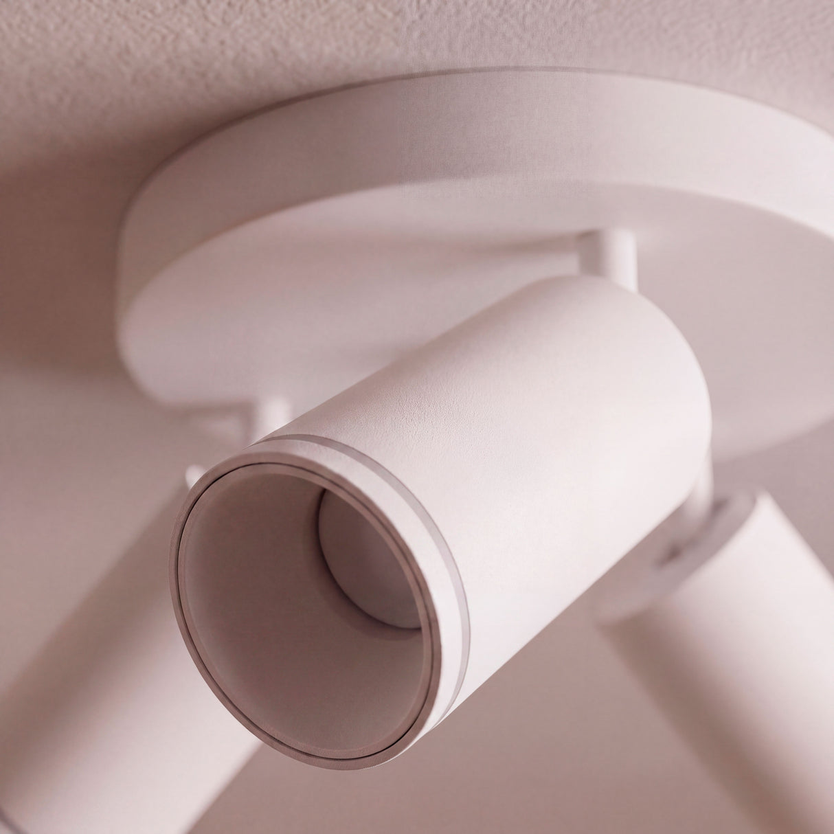 Detalle de cabezal orientable sobreponer en blanco mate para espacios de arquitectura contemporánea.
