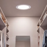 Spot circular empotrado en pasillo de color blanco proporcionando luz técnica uniforme.