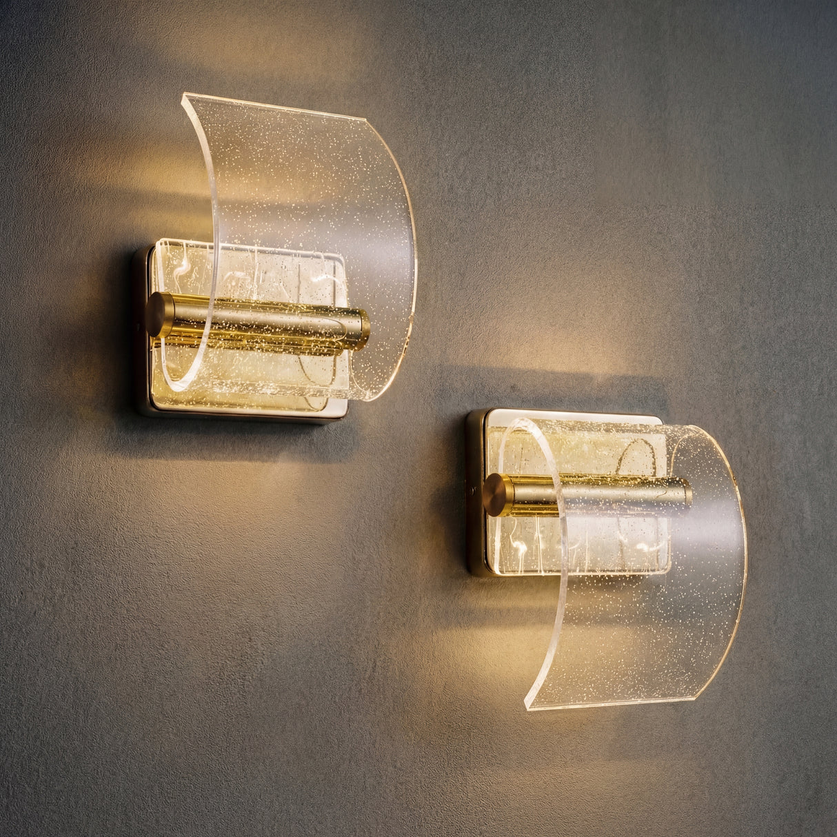 Pareja de apliques LED dorados Wave Gold instalados en pared gris.