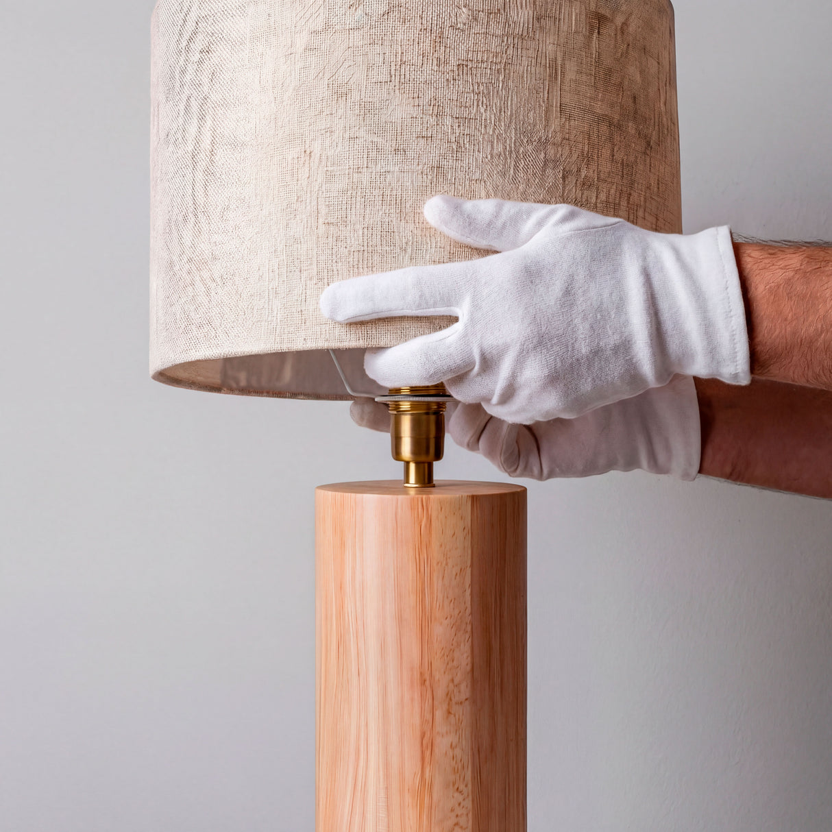 Proceso de ajuste de los herrajes de latón en lámpara de mesa de madera clara.