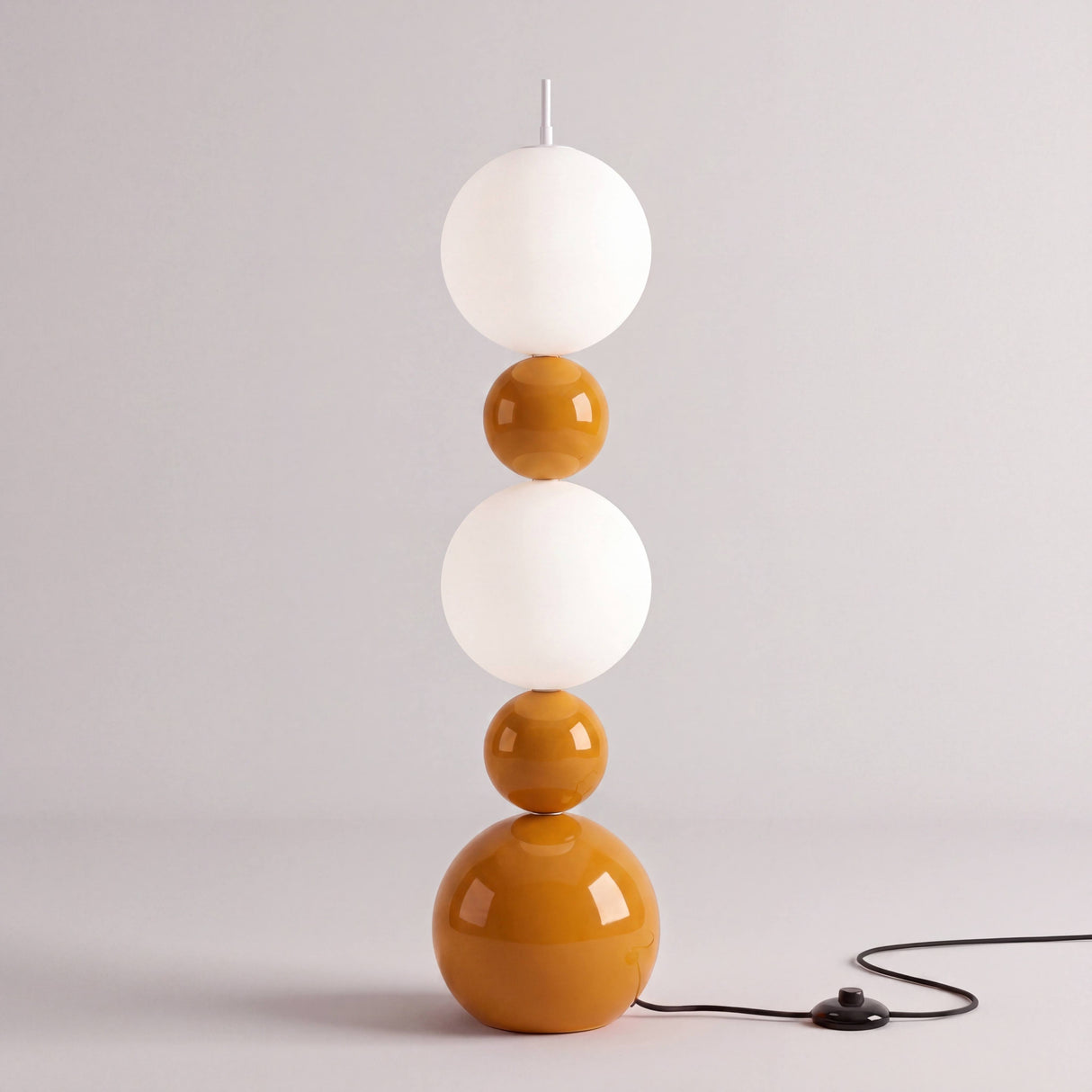 Cuerpo vertical exento de esferas geométricas encendido proyectando una luz suave simétrica.