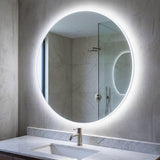 Ambiente de baño con espejo circular retroiluminado que aporta profundidad y diseño minimalista.