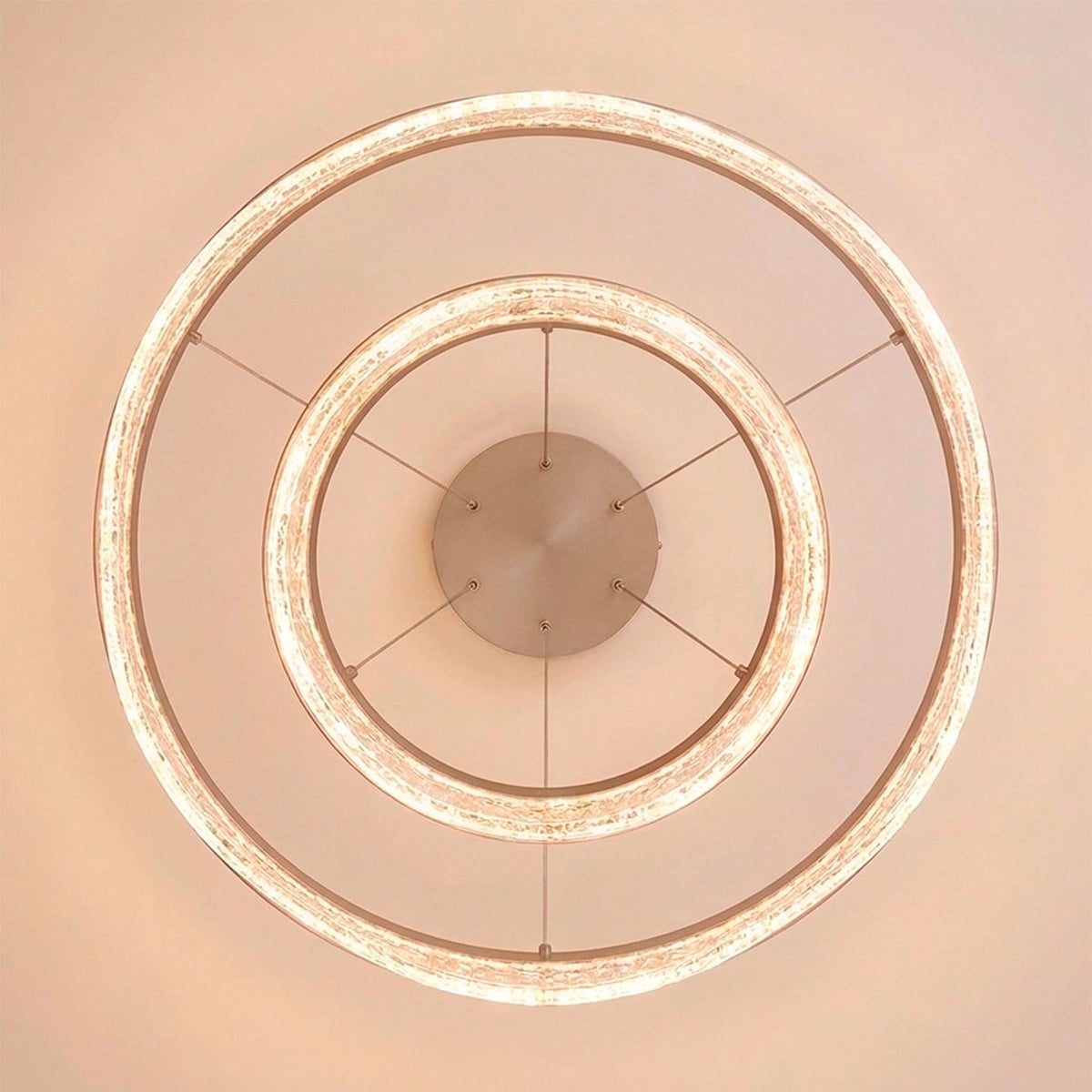 Estructura concéntrica suspendida en acabado rosa con anillos difusores de textura brillante.