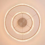 Estructura concéntrica suspendida en acabado rosa con anillos difusores de textura brillante.