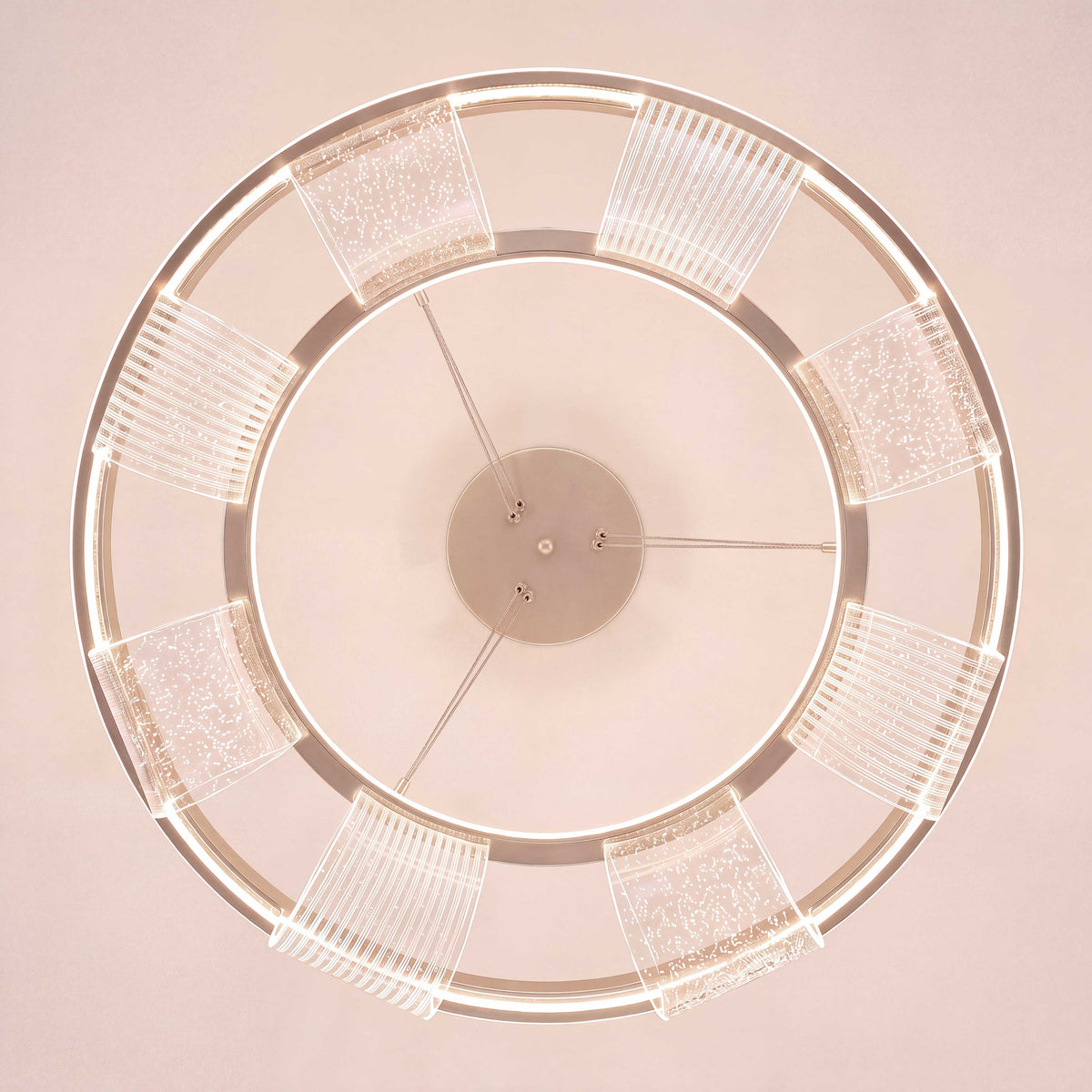 Estructura concéntrica suspendida en acabado rosa con anillo difusor de textura brillante.