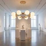Sala de exhibicion con pedestales y arte moderno iluminada por la estructura circular de la lampara Collier.