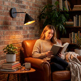 Haz luminoso orientable sobre rincón de lectura que promueve la ergonomía visual y la relajación.