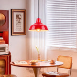 Lámpara colgante roja sobre mesa de madera generando un ambiente acogedor con diseño minimalista.