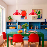 Par de focos colgantes sobre mesa de comedor verde, logrando un balance cromático y confort visual.