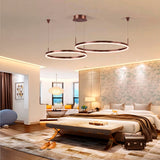 Anillos LED suspendidos sobre cama principal que integran confort óptico y estética contemporánea.
