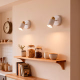Par de focos de pared iluminando repisas de madera con acabados premium en cocina de estilo nórdico.
