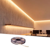 Baño de luz lineal continua sobre muro texturizado en oficinas de diseño minimalista.