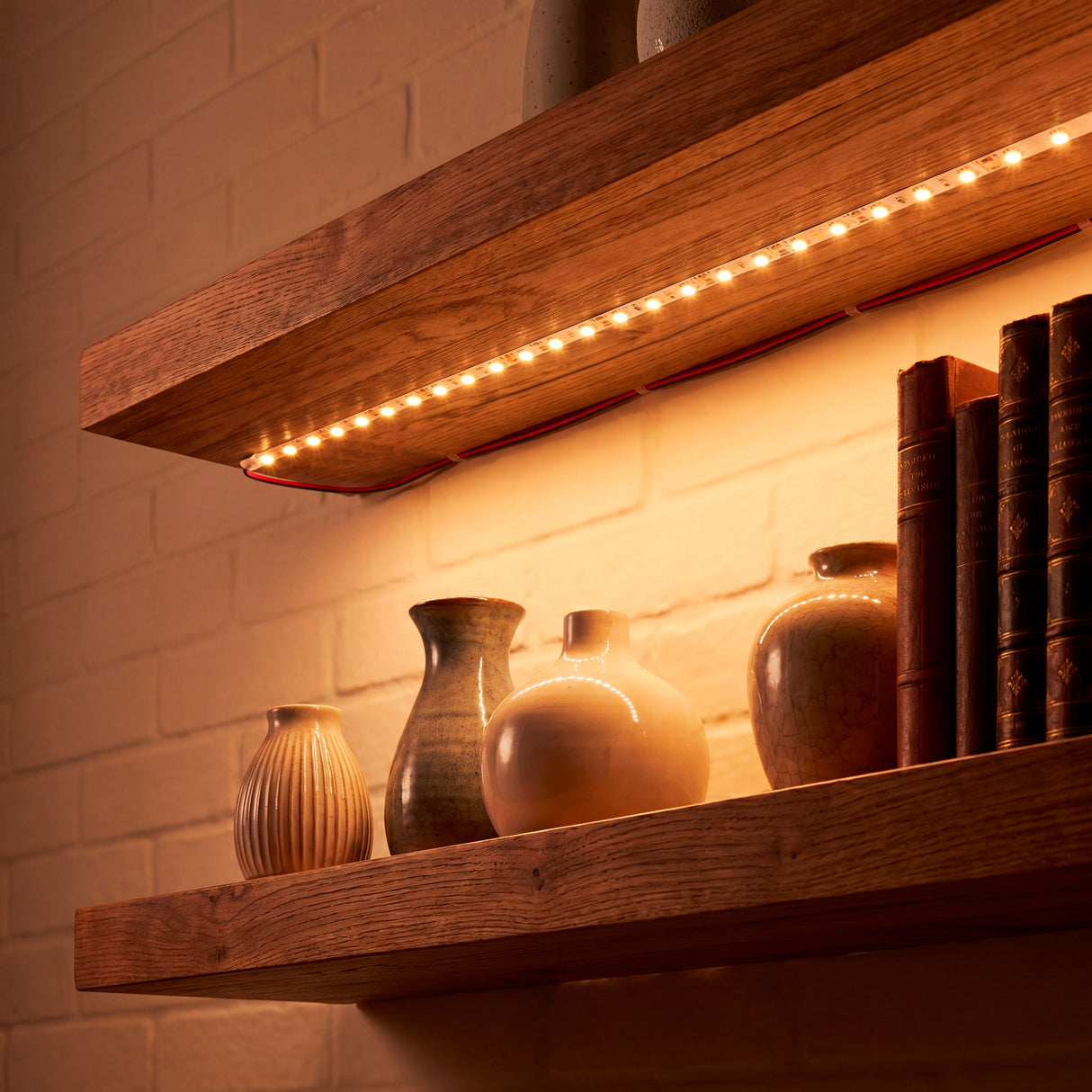 Luz lineal oculta debajo de estantes de madera, optimizando el confort visual y realzando texturas.