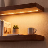 Luz lineal continua oculta debajo de repisa flotante de madera, optimizando la atmósfera residencial.