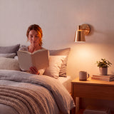 Luz cálida cenital sobre cabecera de cama para crear un ambiente relajante e íntimo de noche.