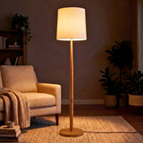 Lámpara de madera decorativa aportando un haz de luz superior e inferior elegante en un rincón de lectura.