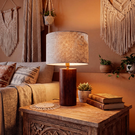 Lámpara de madera de nogal encendida sobre mesa tallada en ambiente de diseño cálido.