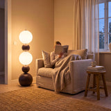 Luz de ambiente suave proyectada por lámpara escultural junto a sofá con manta en salón residencial.