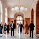 Parejas de gala caminando bajo la imponente presencia de la lámpara Victoria Gold.