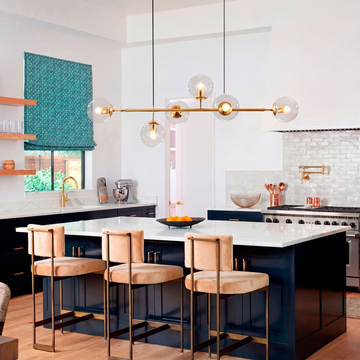 Lámpara dorada horizontal en cocina moderna con isla azul marino y taburetes de cuero.