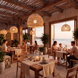 Luminaria de fibras naturales instalada en restaurante frente al mar con mesas de madera.