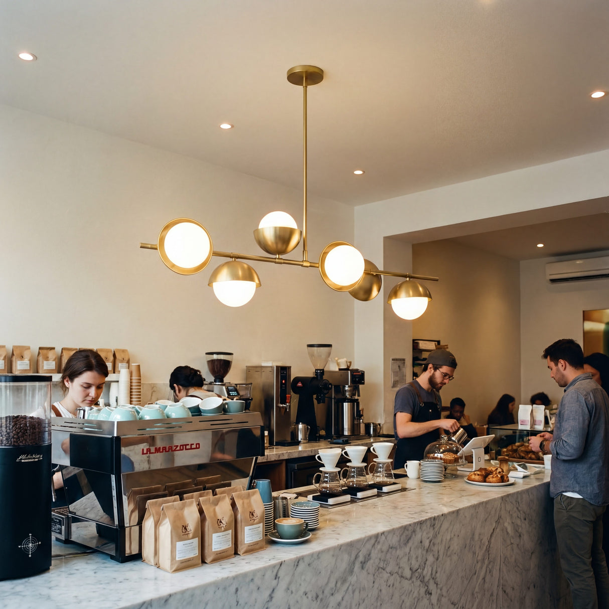 Barra de cafeteria moderna iluminada con la elegancia lineal de la lampara Nova Gold.