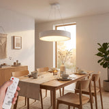 Luminaria de suspensión blanca sobre mesa de comedor de madera en ambiente nórdico.