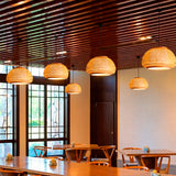 Serie de lámparas Belinda integradas en un techo de listones de madera de un restaurante.