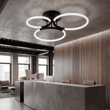 Plafón LED de tres aros negros en mostrador de recepción con paredes de madera.