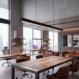 Lámpara lineal sobre mesa de trabajo rústica en oficina de arquitectura con luz neutra.