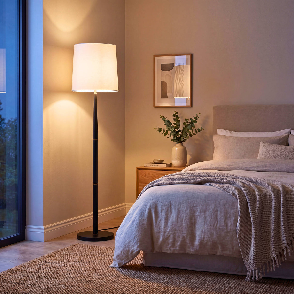Lámpara de suelo esbelta proyectando luz de cortesía acogedora en un dormitorio principal contemporáneo.